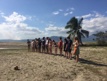 Group of teenagers stand on the beach during an orientation for a trip to Fiji