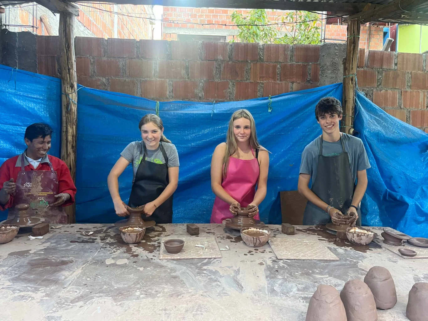 Students shape clay alongside a local artisan at a pottery workshop in Peru's Sacred Valley.