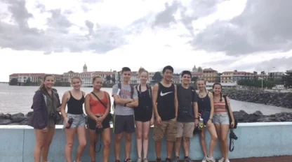 Students sit as a group along a wall near the water in Panama City