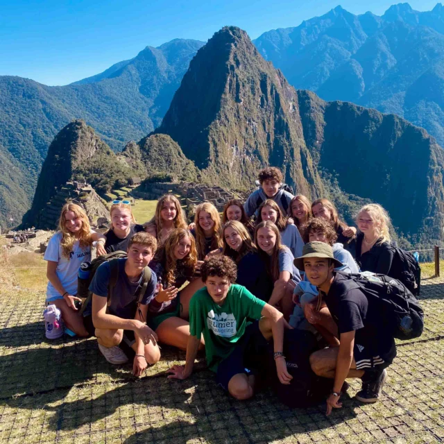 A group of people poses for a photo with Machu Picchu and mountains in the background.