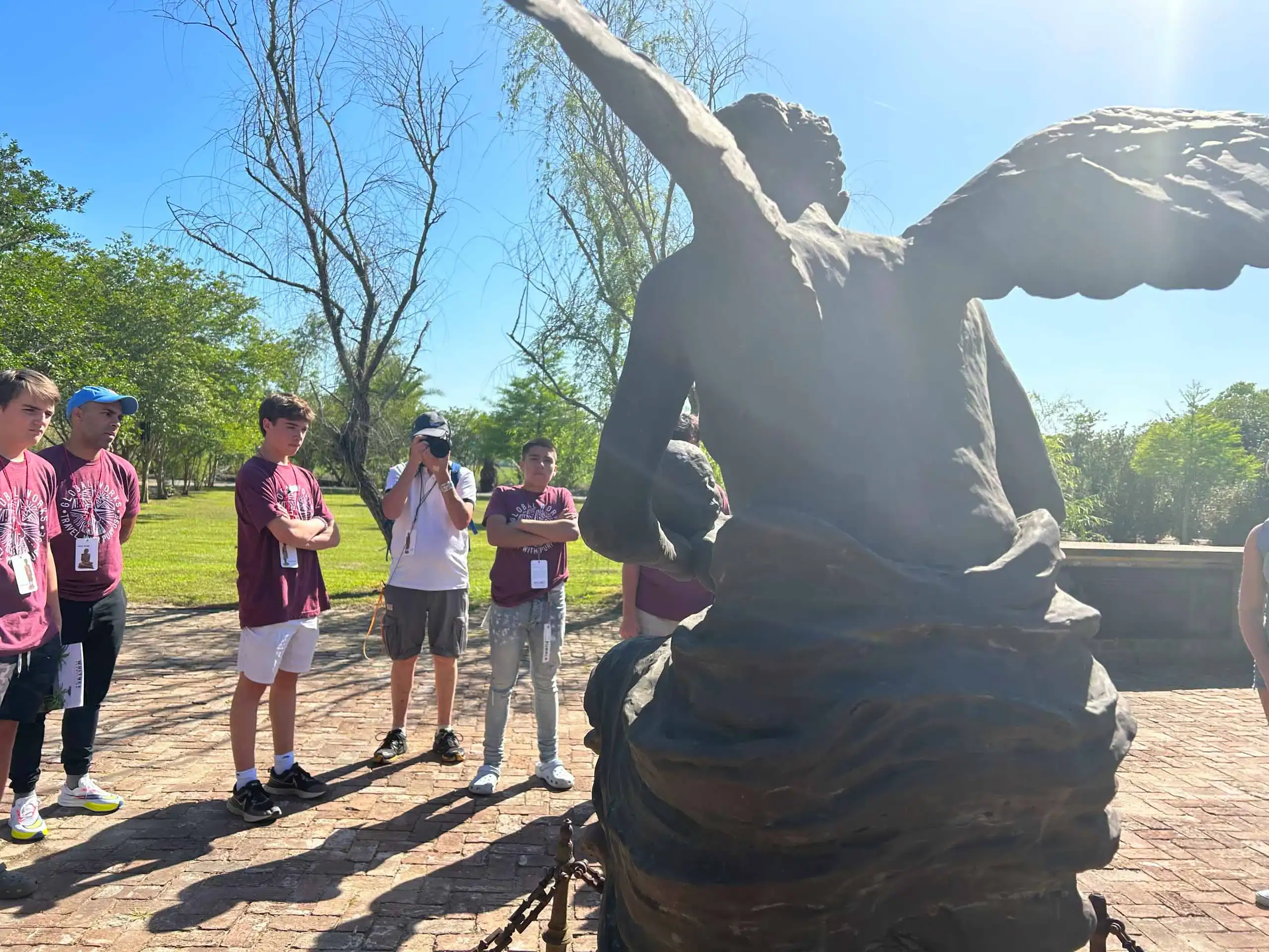 A school group travel outing in the United States with students gathering to observe a statue.