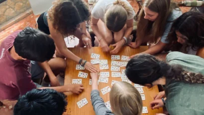 A group of people seated around a table, engaged in a card game.