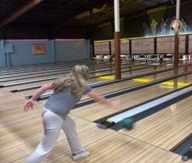A woman bowling in a bowling alley.