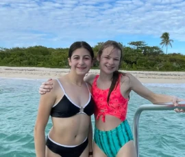 Two girls in swimsuits posing for a picture on a boat.